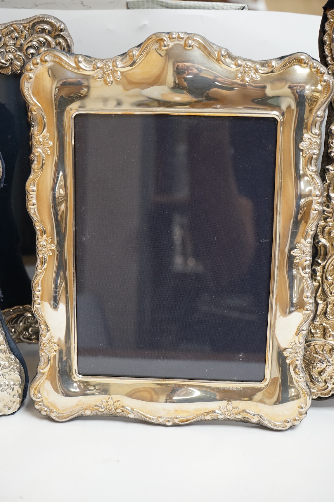 A George V silver mounted rectangular photograph frame, with ribbon bow crest, by Stokes & Ireland Ltd, Chester, 1912, 18.2cm including crest, together with ten other modern silver mounted photograph frames, largest 29.4